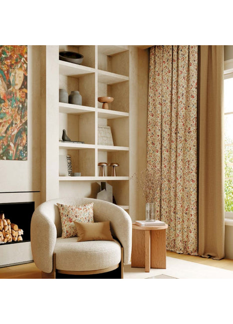 Rideau à fleurs rouges sur fond beige, style champêtre, dans un salon cosy avec fauteuil bouclette et cheminée