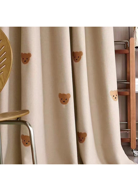 a room with a chair and a curtain with teddy bears on it