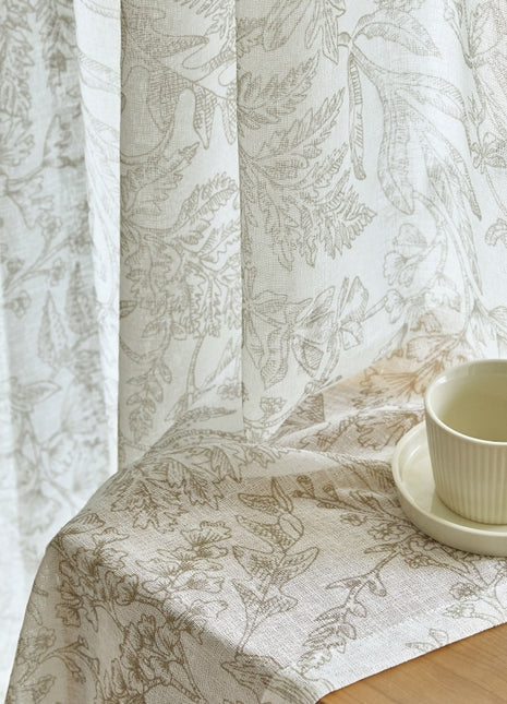 a cup and saucer on a table next to a curtain