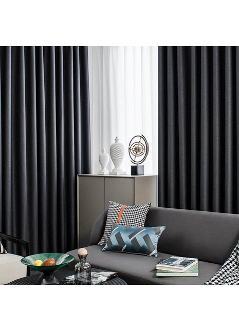 a living room with a gray couch and black curtains