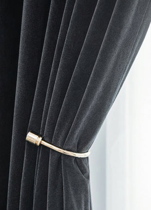 A close-up view of a black velvet curtain with a gold metal rod attached to it.
