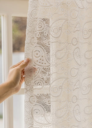 a person is holding a piece of lace in front of a window