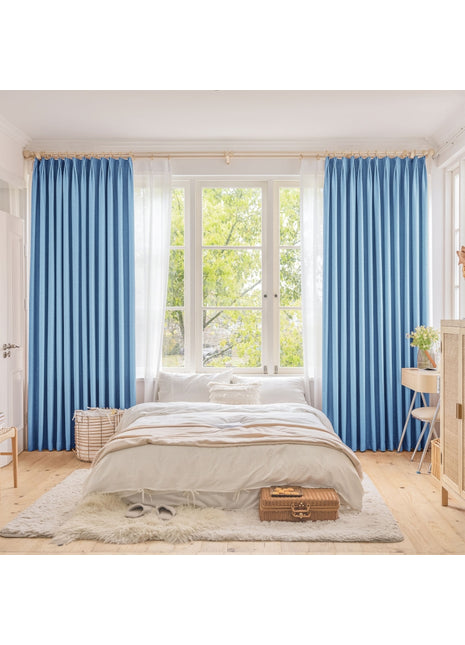 a bedroom with blue curtains and a white bed