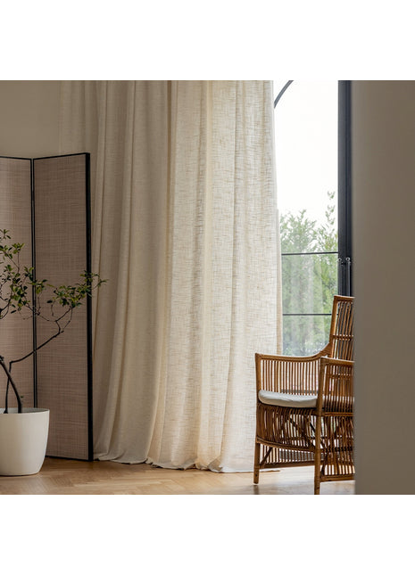 a chair sitting next to a window with a white curtain