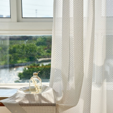 a window with a white curtain and a clock