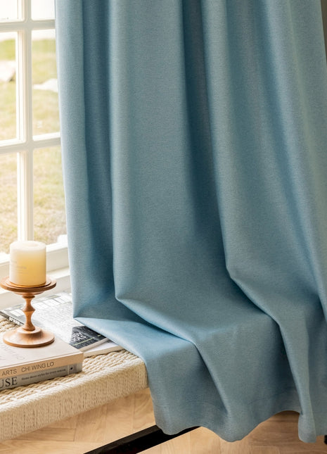 a window with a blue curtain and a candle