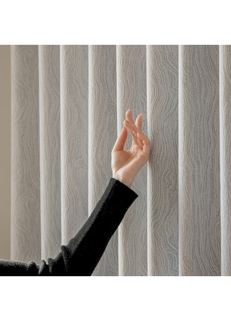 a woman's hand reaching up to a vertical blind
