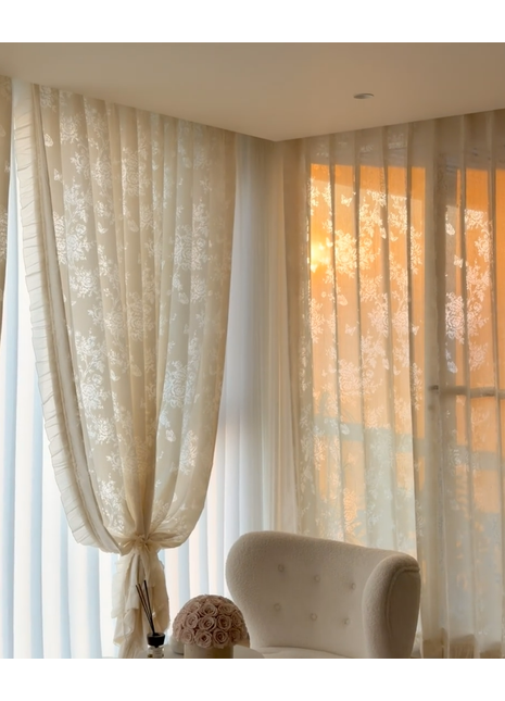 a cozy living room with a plush white armchair, a decorative vase, and a window with sheer curtains.