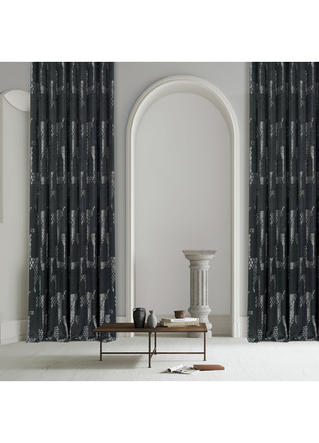 a living room with a table and two black curtains