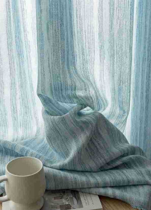 Rideau bleu ciel drapé devant la fenêtre, avec une tasse blanche posée à côté