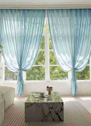 Rideaux bleu ciel embrassés de chaque côté d'une fenêtre de salon, canapé beige