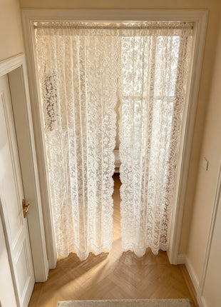 Voilage brodé de style oriental posé en rideau de porte dans un couloir à parquet chevron