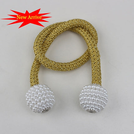 attache perles dorées et blanches sur une corde, utilisée pour des rideaux décoratifs avec attache magnétique.